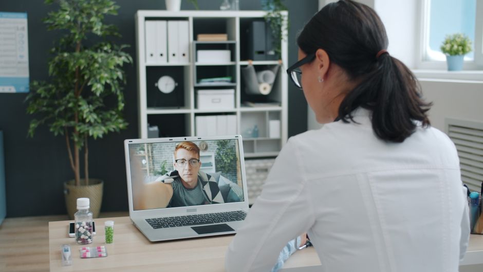 A healthcare professional in a modern clinic interacts with a transparent digital screen displaying health data, symbolizing the intersection of technology and public health.